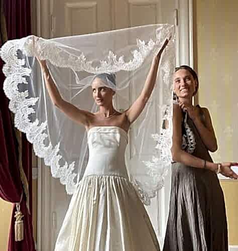 Women in wedding dress holding up her veil.