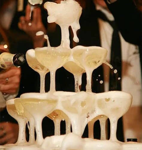 Tower of champagne glasses with champagne being poured onto it