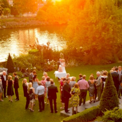 A couple cutting their wedding cake on a riverside at sunset